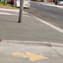 road way with yellow arrow and concrete curb and sidewalk